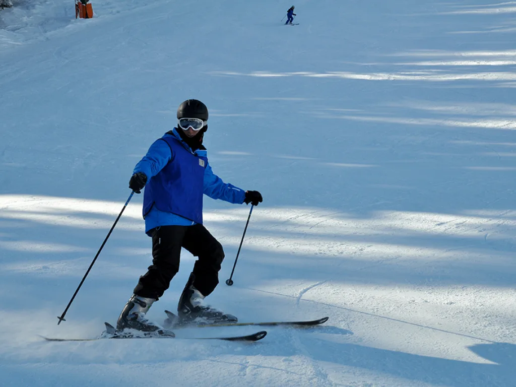 Skifahrer zieht einen Schwung auf der sonnigen Piste.